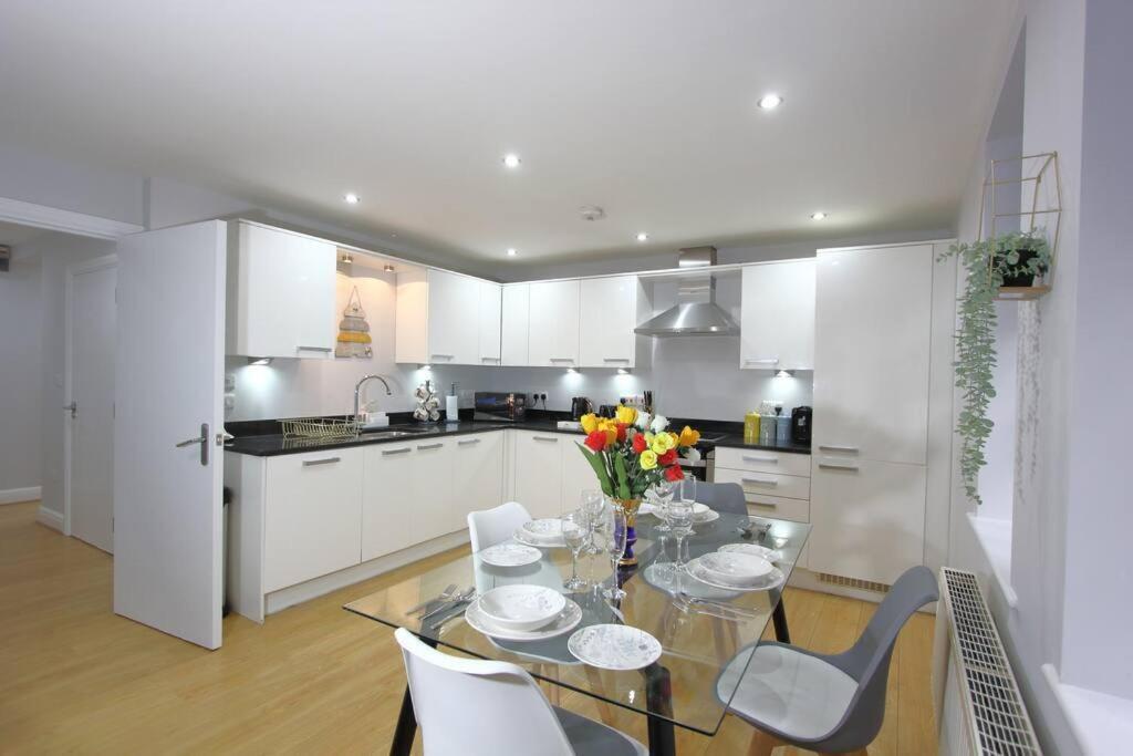 a kitchen with a glass table and chairs and a kitchen with white cabinets at Gorgeous 2 Bed 2 Bath Flat and Parking by CozyNest in Reading