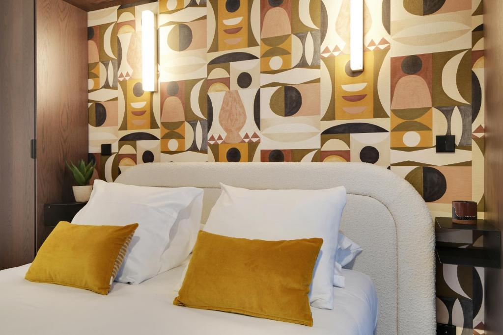 a bedroom with a white bed with two yellow pillows at CMG - La Butte Montmartre in Paris
