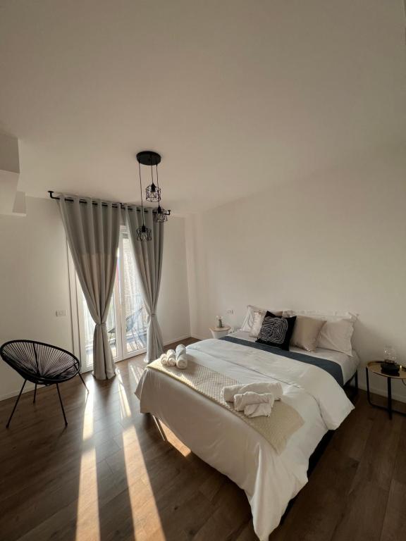 Appartamento Business Milano في ميلانو: غرفة نوم بيضاء مع سرير كبير ونافذة