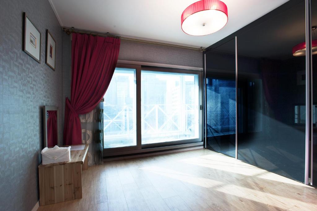 un salon avec une grande fenêtre et des rideaux rouges dans l'établissement Myeongdong Ecohouse, à Séoul