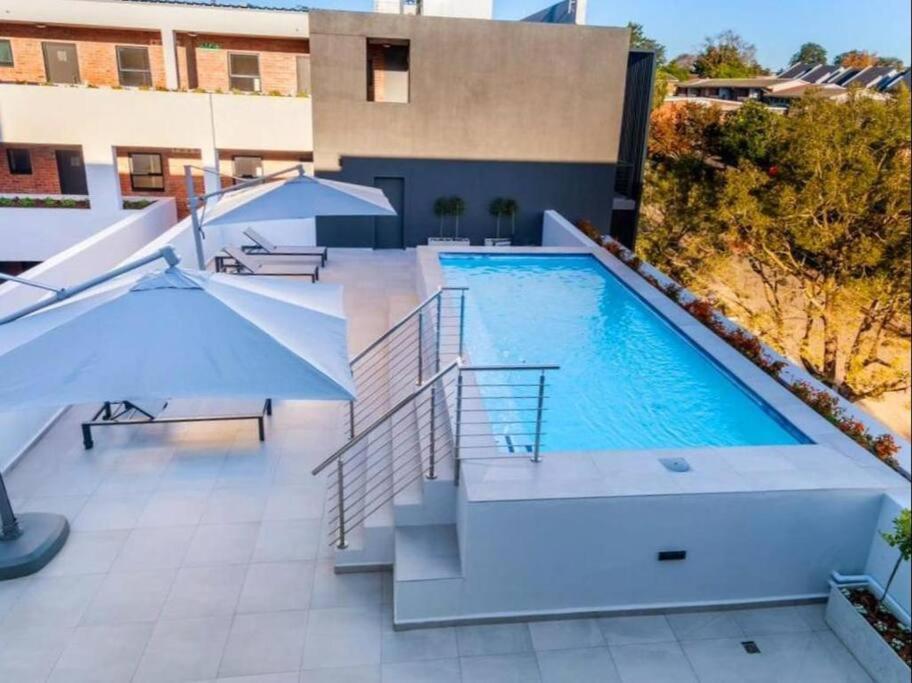 una piscina con escaleras y sombrillas junto a un edificio en 304 Le Jardin en George