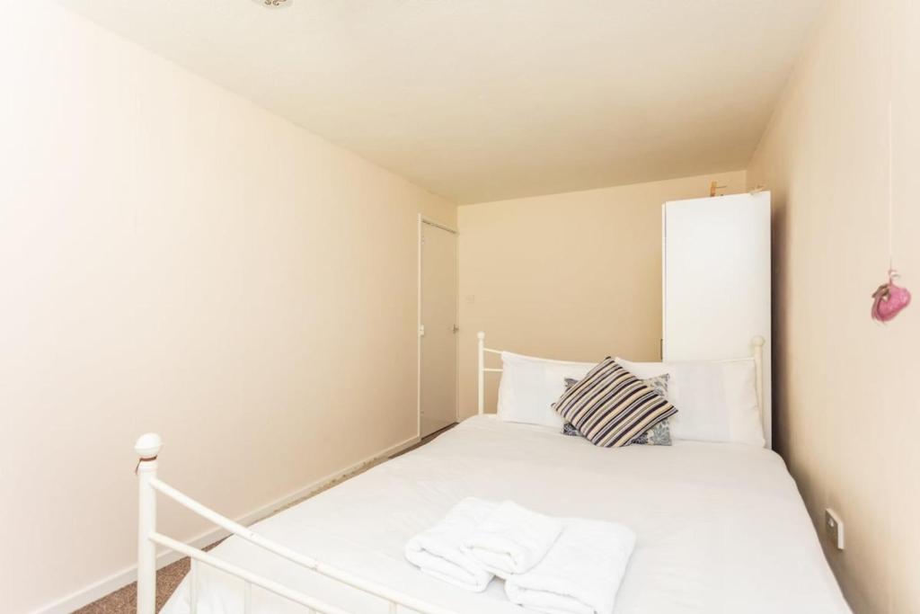 a small bedroom with a bed with white sheets at Spacious 2BD House wPrivate Garden - Kennington! in London