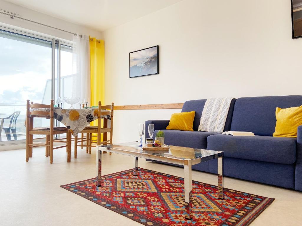 salon z niebieską kanapą i stołem w obiekcie Atlantique, Appartement vue mer classé 2 étoiles à Carnac Plage w mieście Carnac