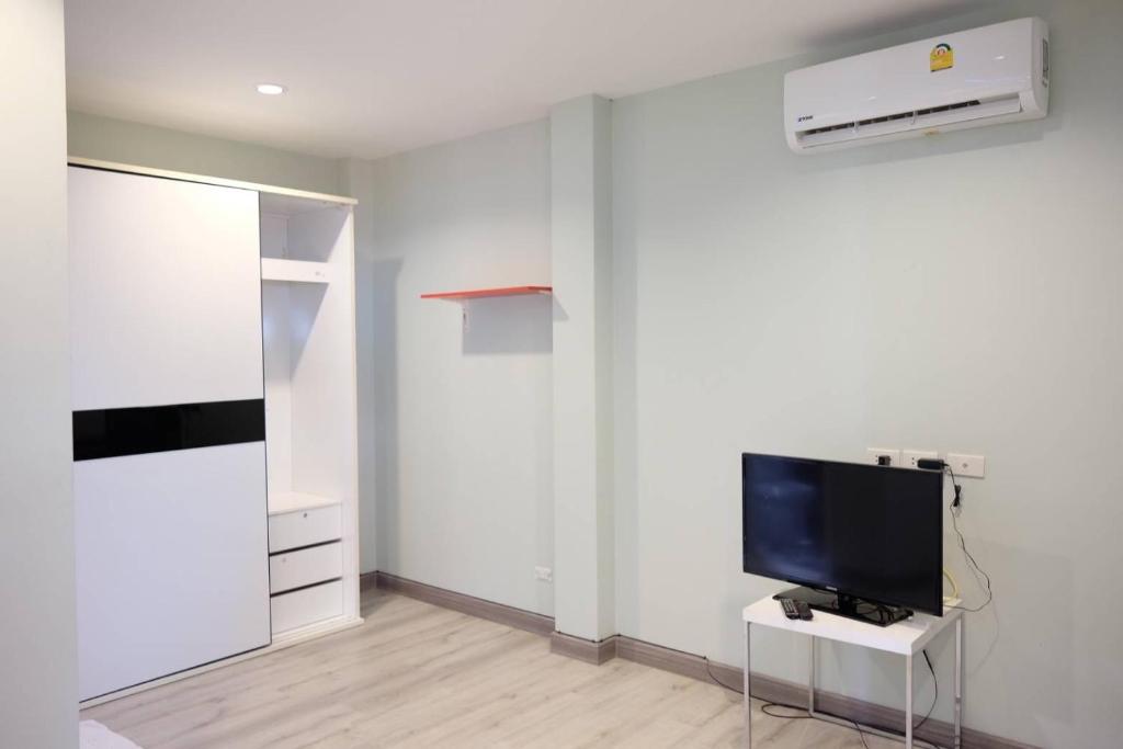 un salon avec une télévision et un mur blanc dans l'établissement วิลล่าพอใจ, à Chiang Mai