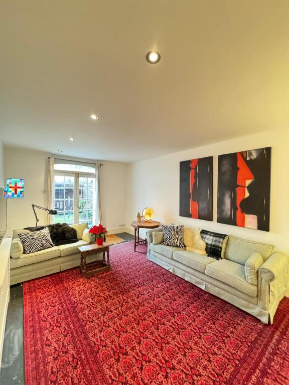 salon z 2 kanapami i czerwonym dywanem w obiekcie Spacious 4BD Family Home with GardenKensal Green! w Londynie