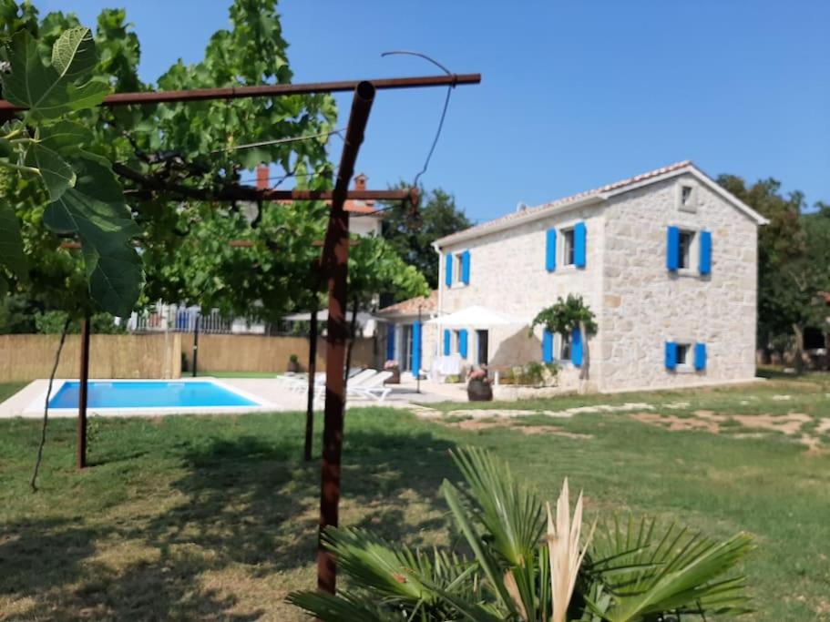 een stenen huis met blauwe ramen en een zwembad bij Villa Laura - Home Away From Home in Labin