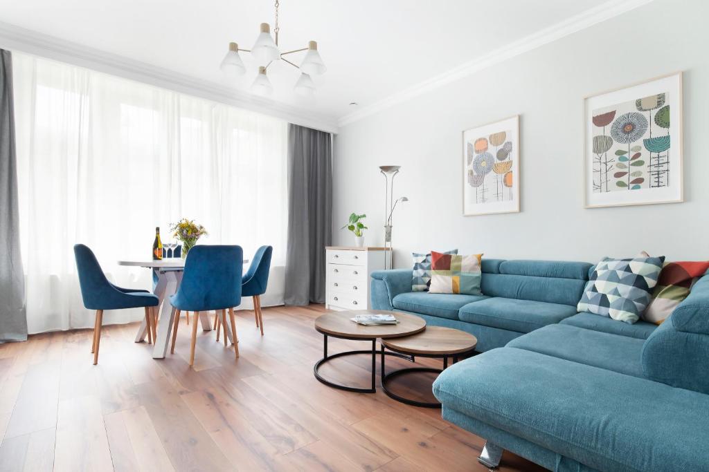 a living room with a blue couch and a table at Elite Apartments Sopot Superior in Sopot