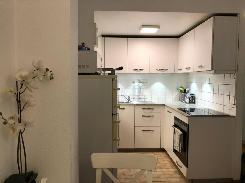 una cucina con armadi bianchi e una sedia bianca di Central 2 bedroom flat in heart of Eaux-vives a Ginevra