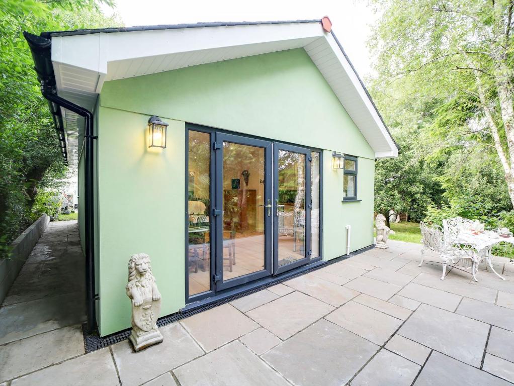 a green house with glass doors and a patio at Purrfect Retreat in Bugle