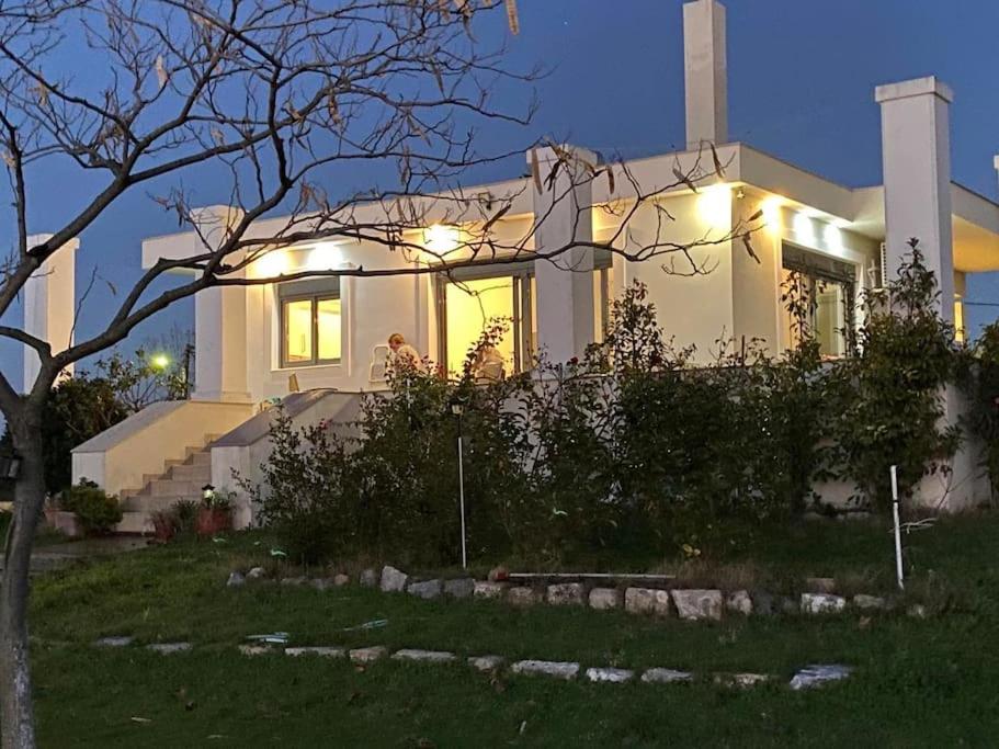 uma casa branca com luzes na frente em Μονοκατοικία με θέα στη θάλασσα και κήπο em Chalkida