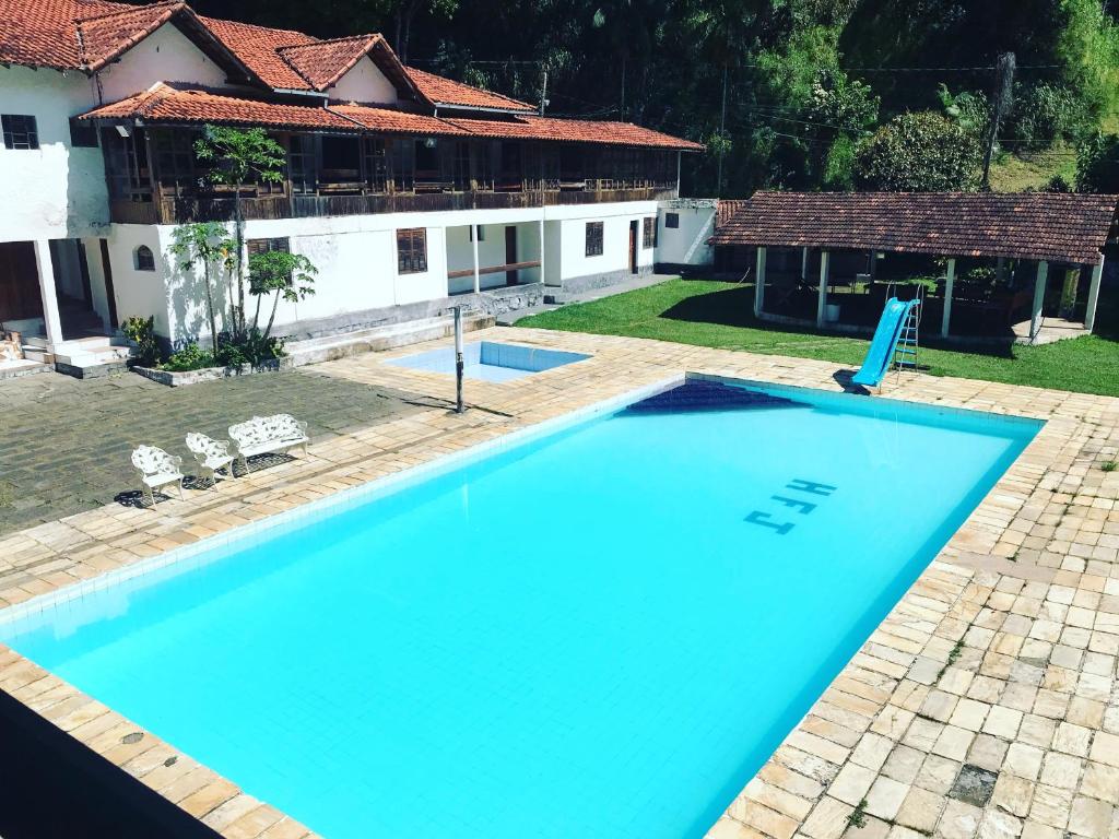 a large blue swimming pool in front of a house at Espaço jequitibá Casa in Nova Friburgo