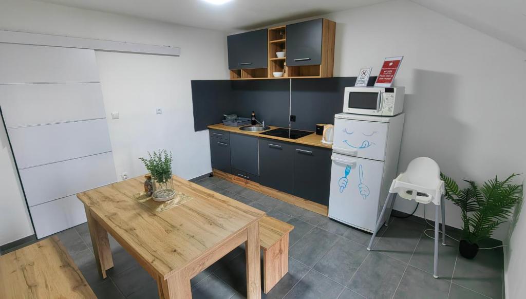 Il comprend une cuisine équipée d'une table en bois et d'un réfrigérateur. dans l'établissement Rooms Osmica- Videm pri Ptuju, à Videm pri Ptuju