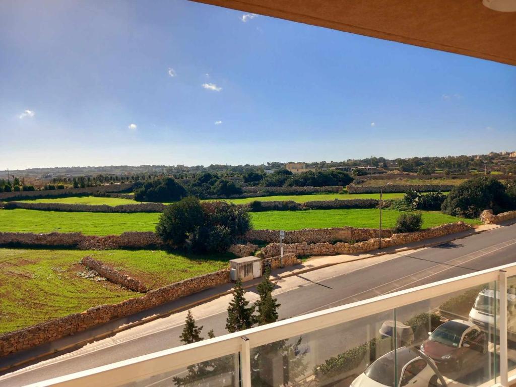 a view of a road and green fields from a balcony at Apartment in Marsaskala in Marsaskala