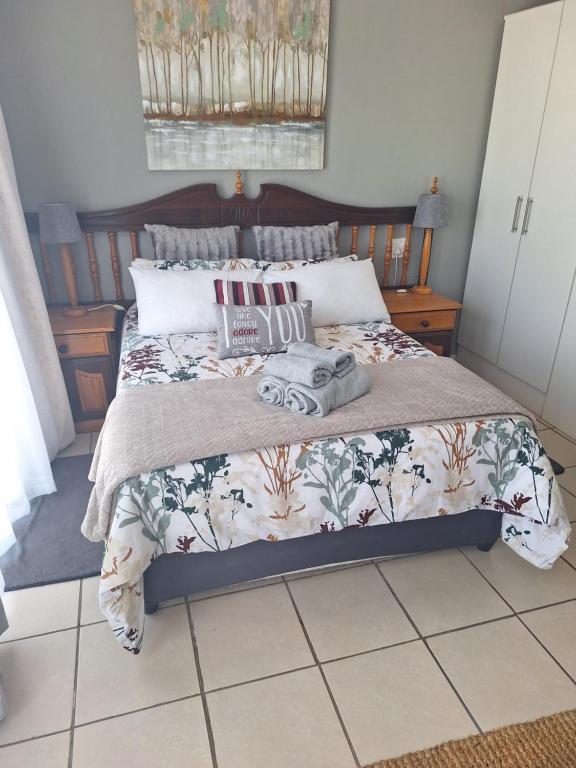1 dormitorio con 1 cama con manta y almohadas en 7 Diaz, en Mossel Bay