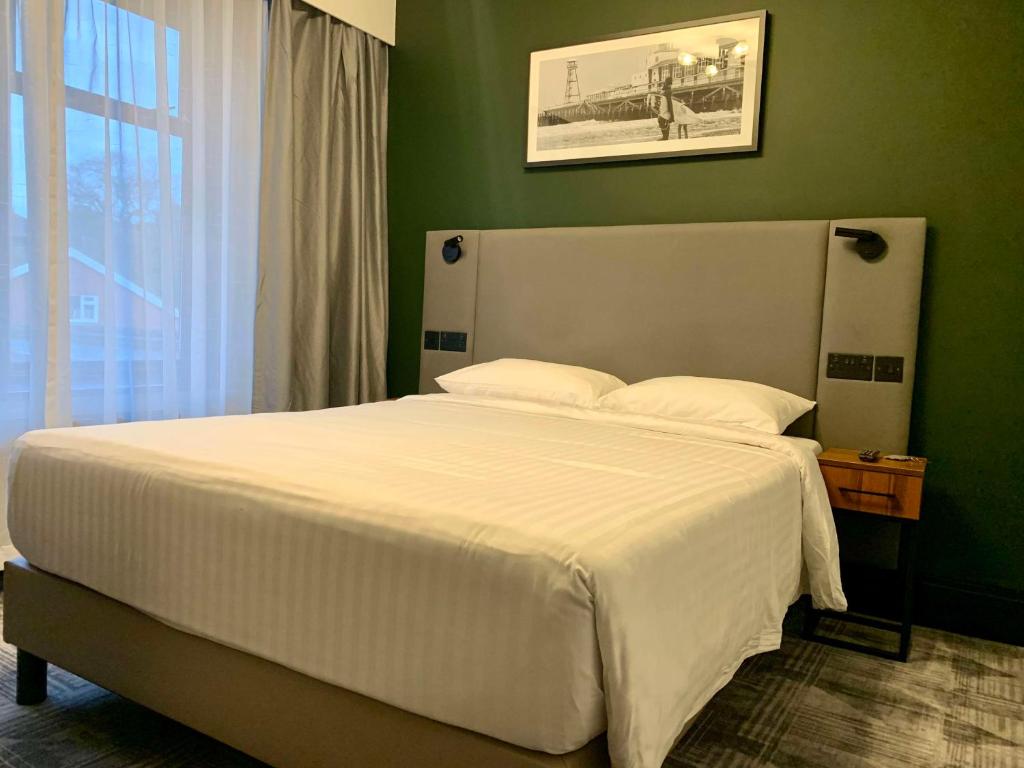 a bedroom with a white bed with a green wall at Park Inn by Radisson Bournemouth in Bournemouth