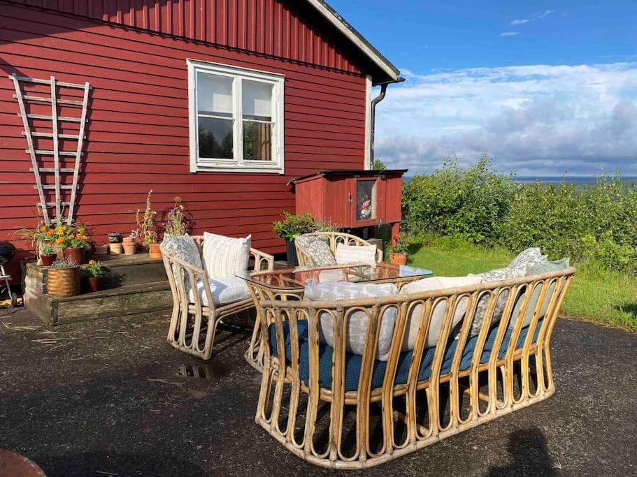 a red house with chairs and a table in front of it at Cozy Hilltop Cottage With Fantastic View in Undenäs