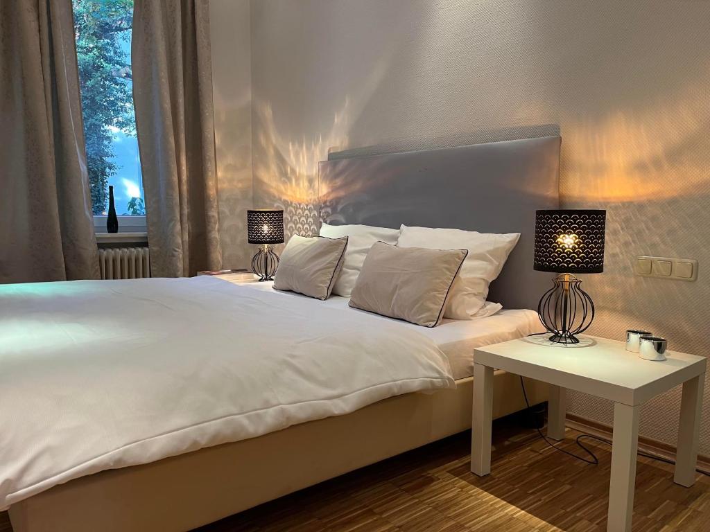 a bedroom with a white bed and a table with lamps at Suite Appartement Friesenhof in Hannover