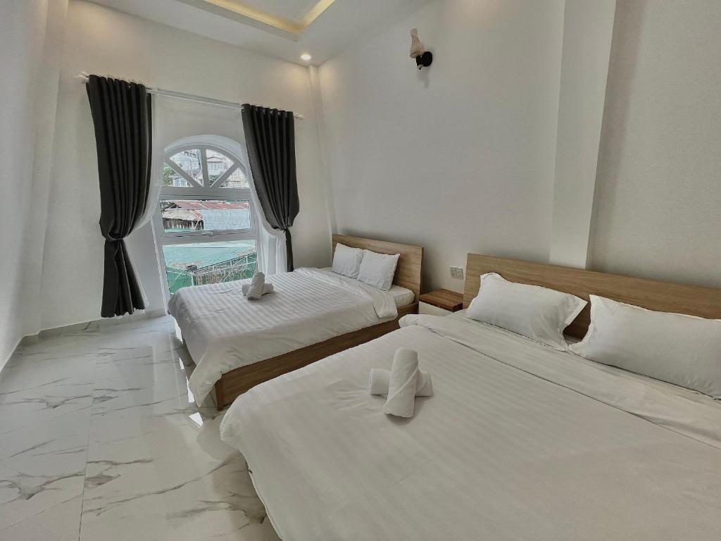 two beds in a room with a window at CT Villa in Xuan An