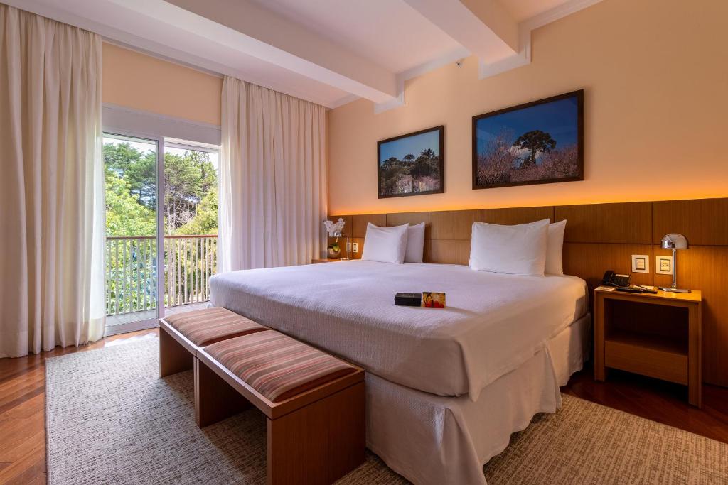 a hotel room with a large bed and a window at Grande Hotel Campos do Jordao in Campos do Jordão