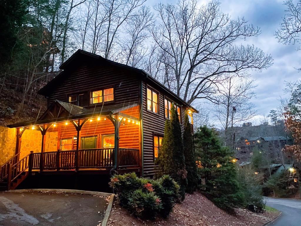 uma pequena casa com luzes na frente em Spacious Resort Log Cabin, Easy Drive, Hot Tub, Arcade Gameroom, Mountain Vibe em Gatlinburg