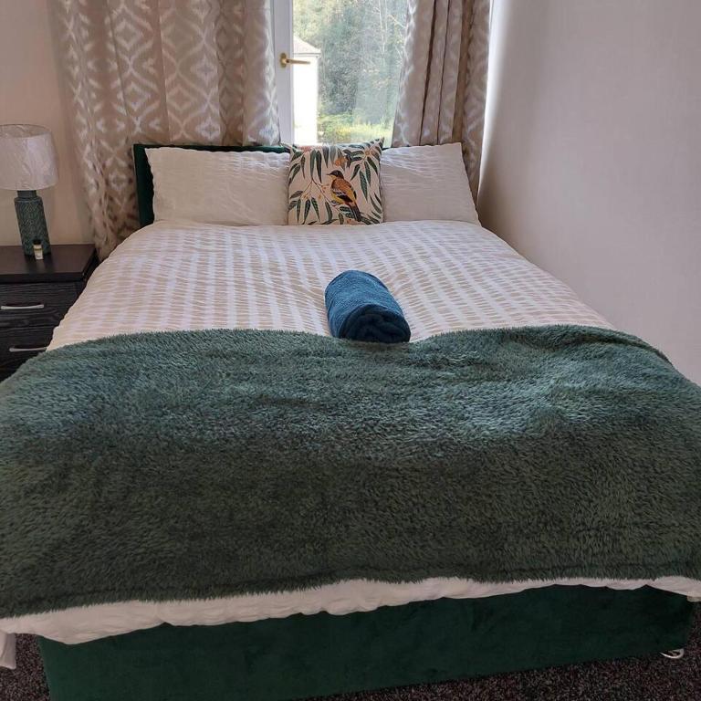 a bed with a green blanket and a hat on it at 4-Bed House in Accrington in Accrington