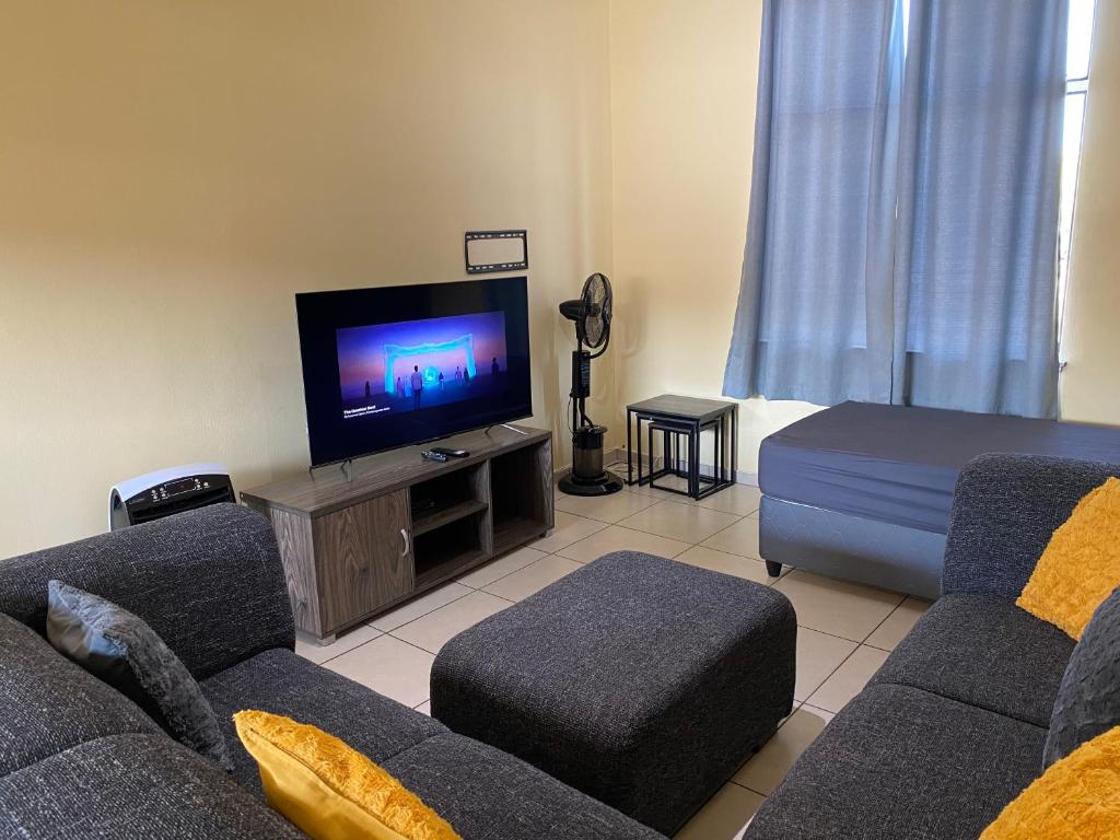 a living room with a couch and a flat screen tv at Unit 11 - Damara Gardens in Windhoek