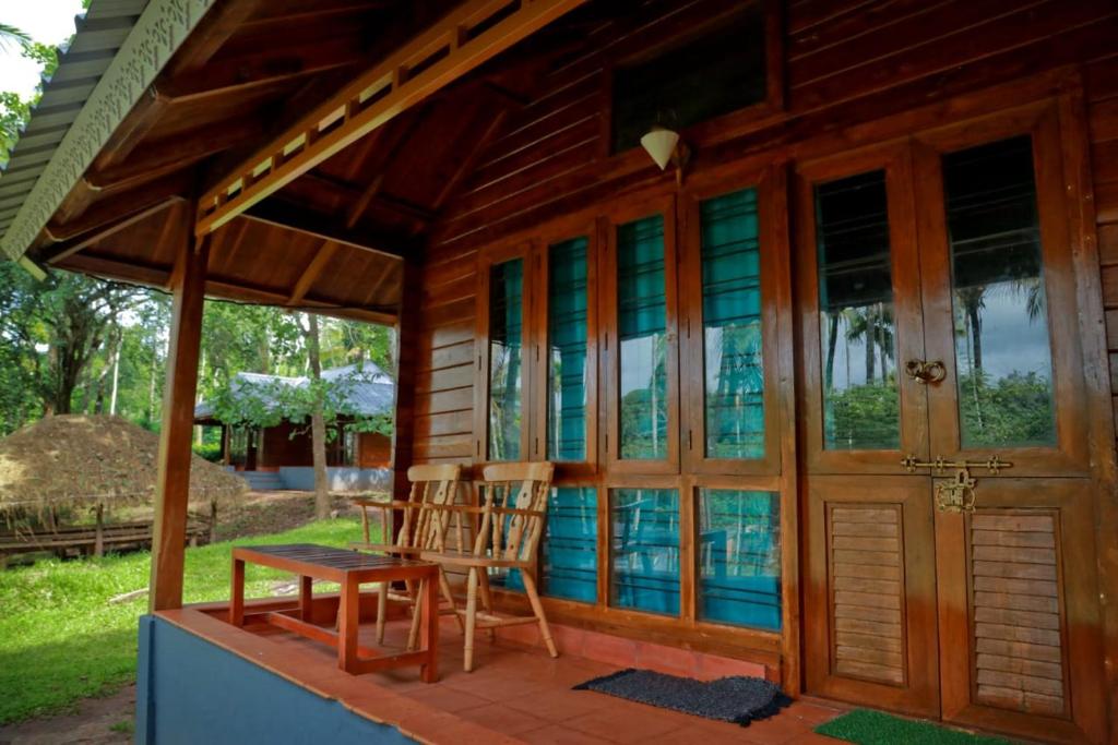 a porch of a house with a table and chairs at Royal Wooden villa in Mananthavady