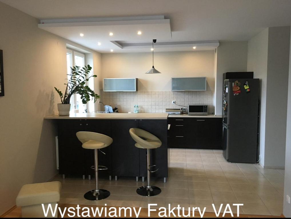 ワルシャワにあるApartament w Wesołejのキッチン(黒い冷蔵庫、スツール2台付)