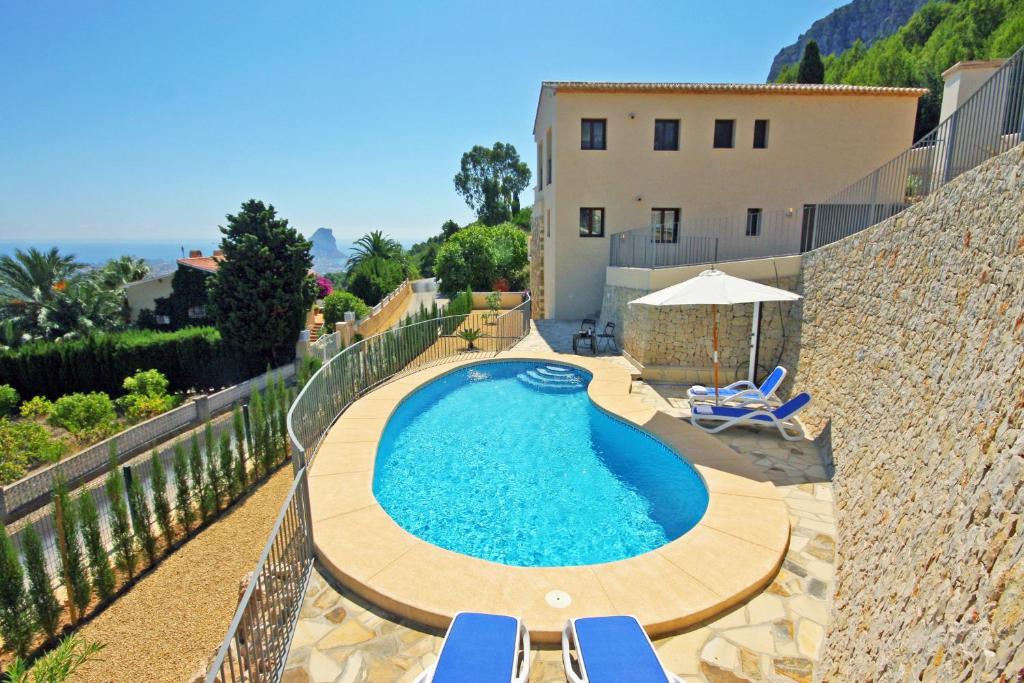 una piscina con sillas azules y un edificio en Villa Lia - PlusHolidays, en Calpe