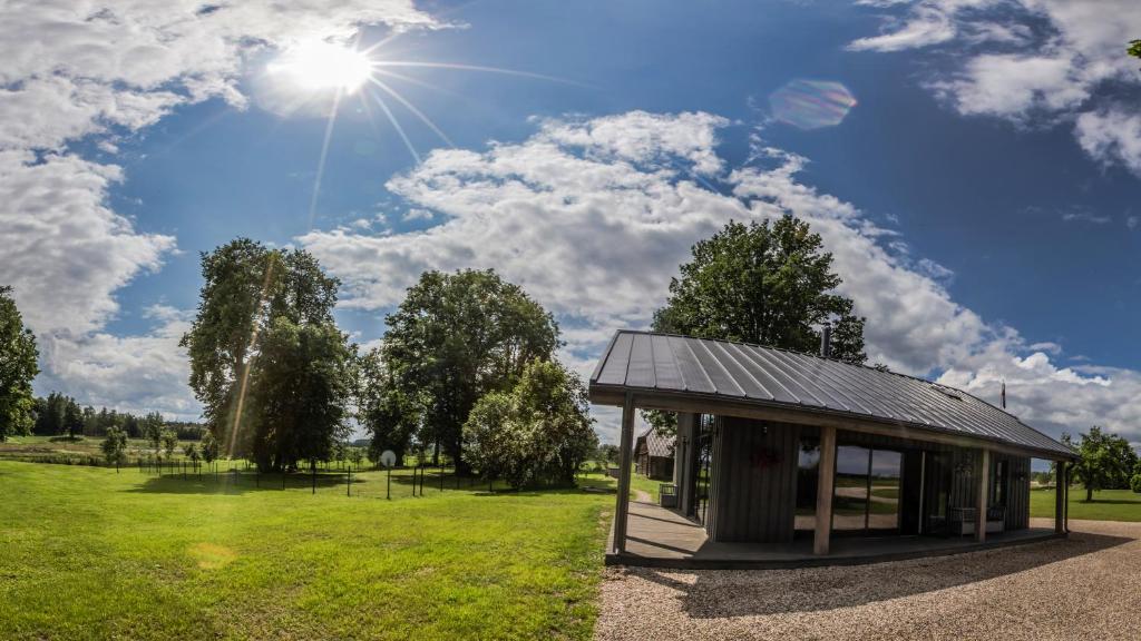 ein Gebäude auf einem Feld mit der Sonne am Himmel in der Unterkunft Holiday home Uzbazes in Valmiera