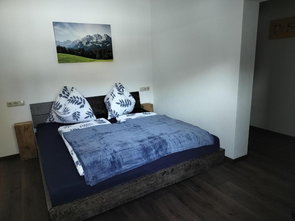 a bedroom with a bed with blue sheets and pillows at Ferienwohnung Ortner in Sankt Johann in Tirol