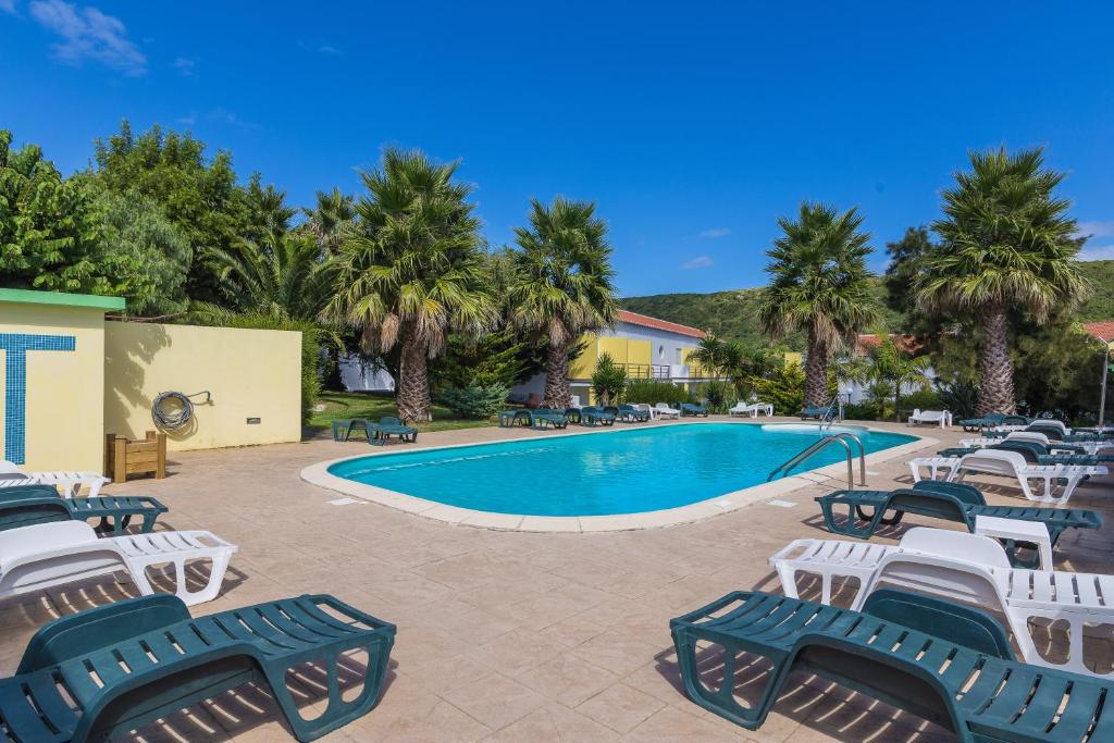 a pool with chaise lounge chairs next to a resort at Hotel Teresinha in Praia da Vitória