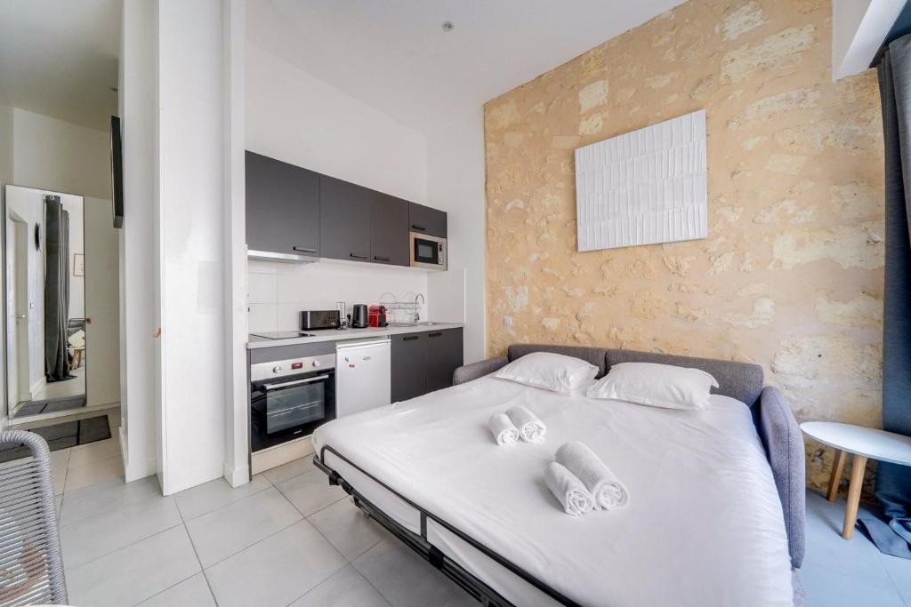Cet appartement comprend une chambre avec un lit blanc et une cuisine. dans l'établissement Beautiful apartment Bordeaux with private terrace, à Bordeaux