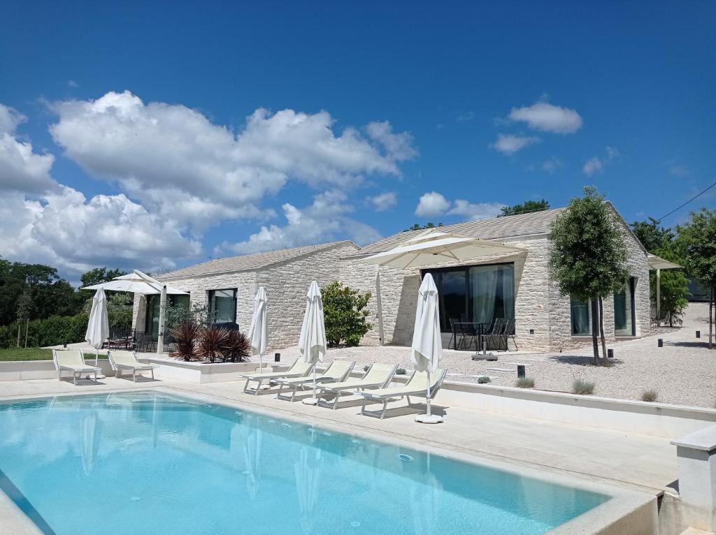 een zwembad met stoelen en parasols voor een huis bij Terra Histria - Boutique Stone House in Oprtalj