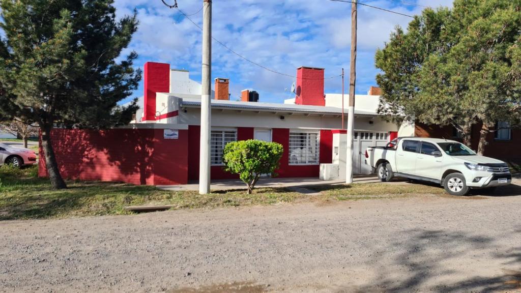 biała ciężarówka zaparkowana przed czerwonym domem w obiekcie Sonidos del Mar w mieście Balneario El Condor