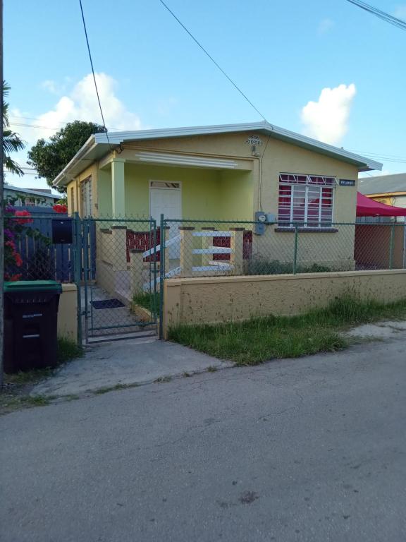 una casa amarilla con una valla delante de ella en Caribb Home and Taxi Service, en Bridgetown