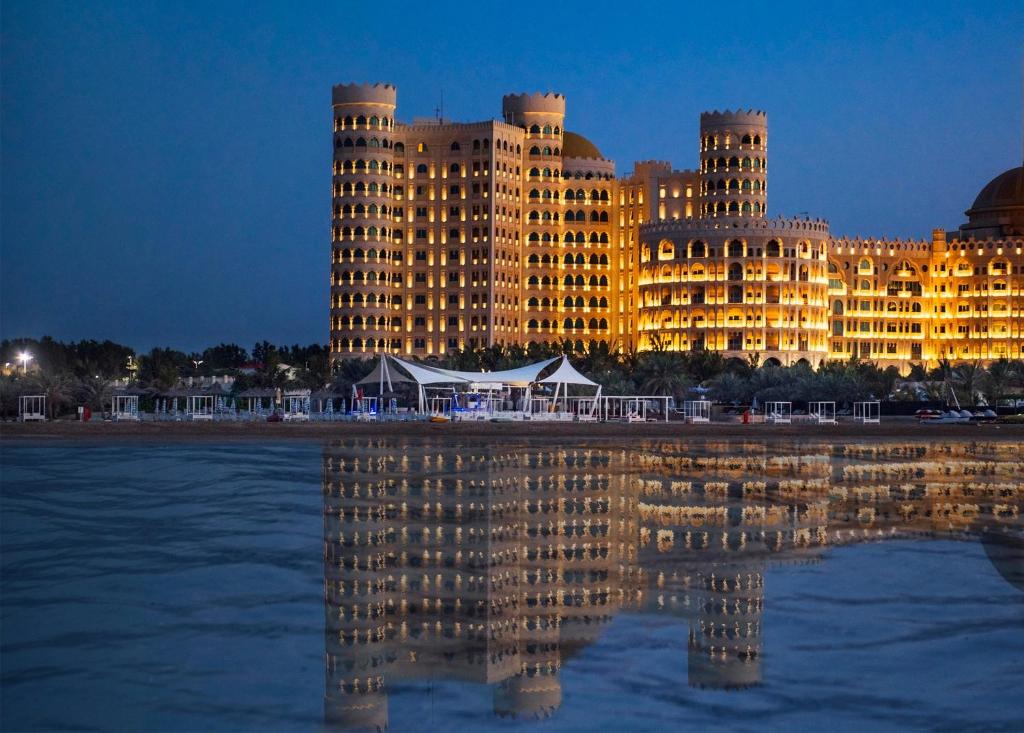 un grand bâtiment avec une réflexion dans l'eau dans l'établissement Al Hamra Residence, à Ras al Khaimah