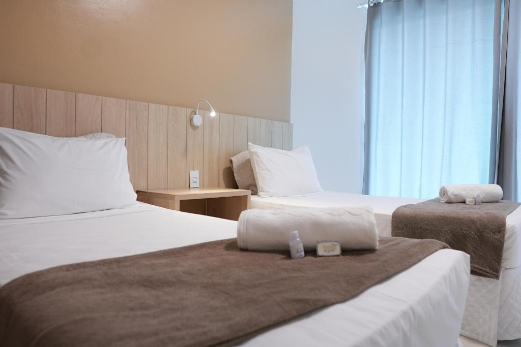 a hotel room with two beds with towels on them at Pousada Areia do Forte in Cabo Frio