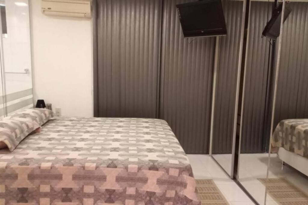 Loft em Belém في بيليم: غرفة نوم بسرير وتلفزيون بشاشة مسطحة