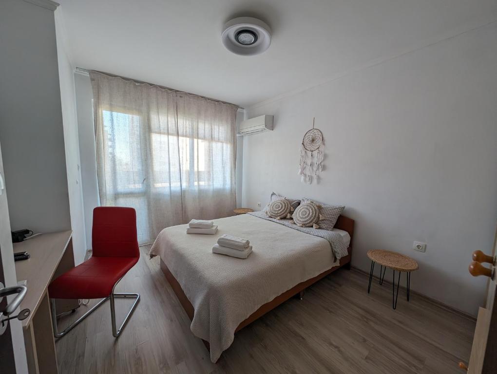 a bedroom with a bed and a red chair at Mila's Home in Burgas