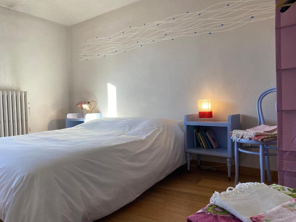 - une chambre avec un grand lit blanc et du parquet dans l'établissement Kiki's, à Castagnole Lanze