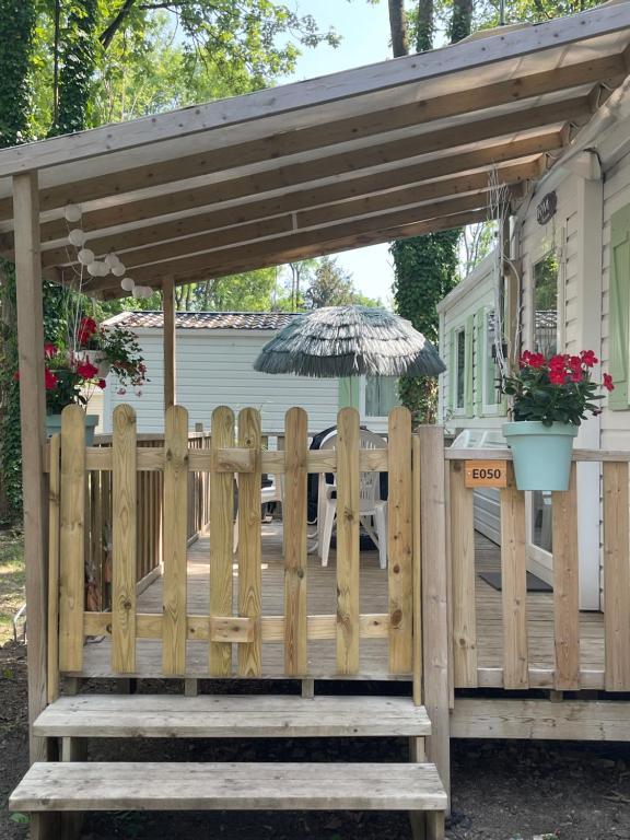 une terrasse en bois avec un parasol et une clôture dans l'établissement mobil home 6 personnes situé à 15 mn d europa park et rulantika, à Boofzheim