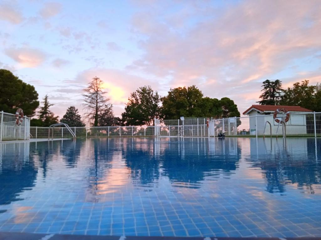 an empty swimming pool with a sunset in the background at Albergue Zaragoza Camping in Zaragoza