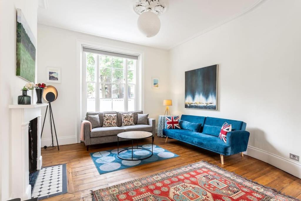 ein Wohnzimmer mit einem blauen Sofa und einem Kamin in der Unterkunft 2-bedroom split-level apartment in Notting Hill in London