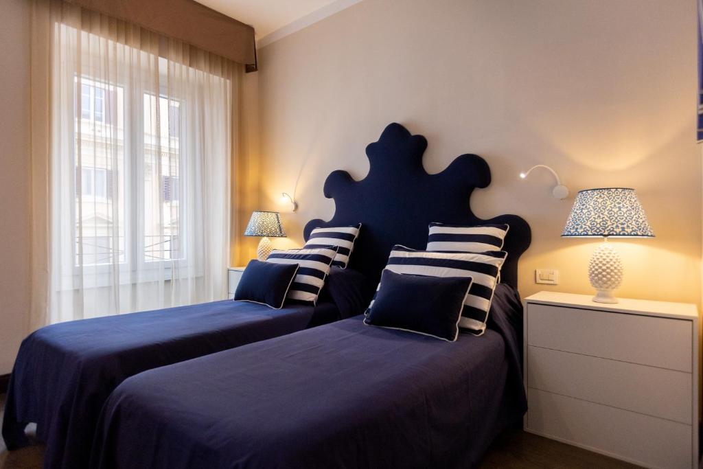 a bedroom with three beds with blue sheets and a window at Relais Piazza Del Popolo in Rome