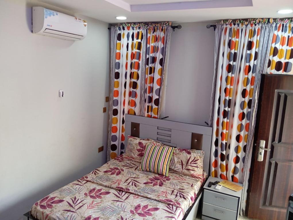 ein Schlafzimmer mit einem Bett und Vorhängen sowie einem Fenster in der Unterkunft Frontline Homes & Suites in Lekki