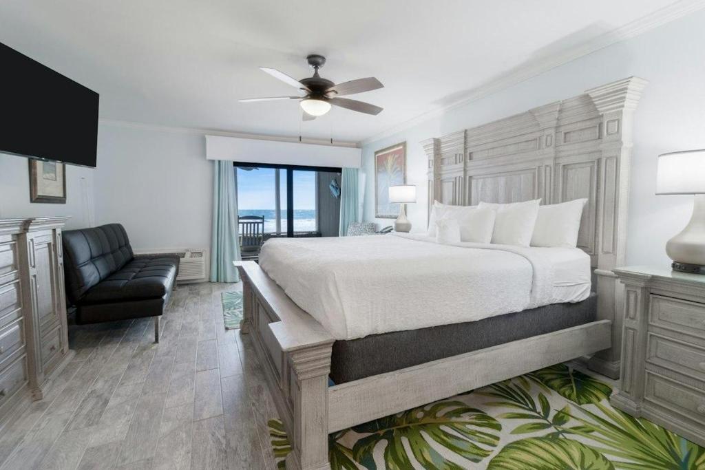 a bedroom with a bed and a chair and a window at Oceanfront Views, Private Porch, 1st Flr, King Bed in Pawleys Island