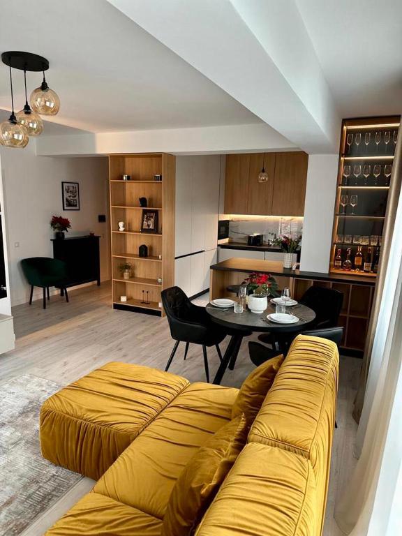 a living room with a yellow couch and a table at Balcescu Downtown Apartment in Bistriţa