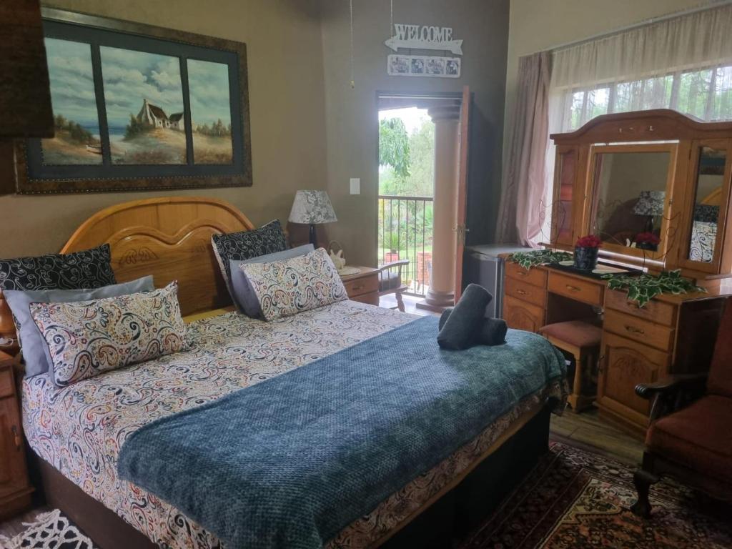 Schlafzimmer mit einem Bett, einer Kommode und einem Spiegel in der Unterkunft Big Boma Guest House in Lydenburg