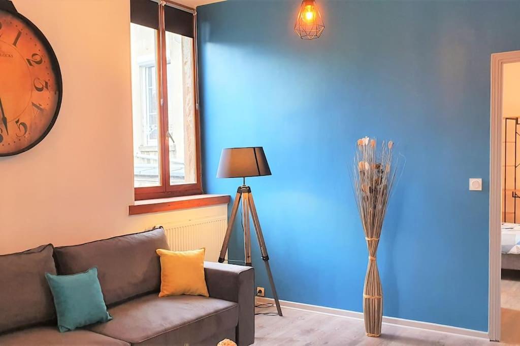 a living room with a couch and a blue wall at Cocon Rue Ecuyère - Calme- 2ch - 6pers in Caen